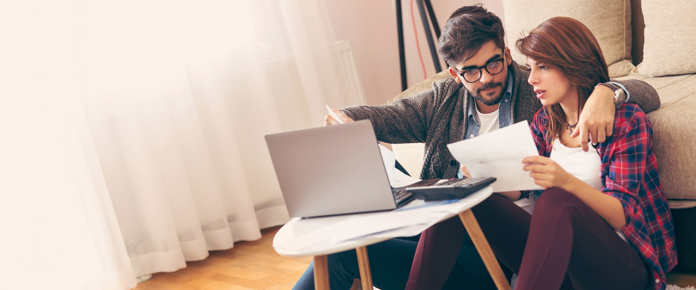 Photo of couple at small coffee table looking at an open laptop computer.