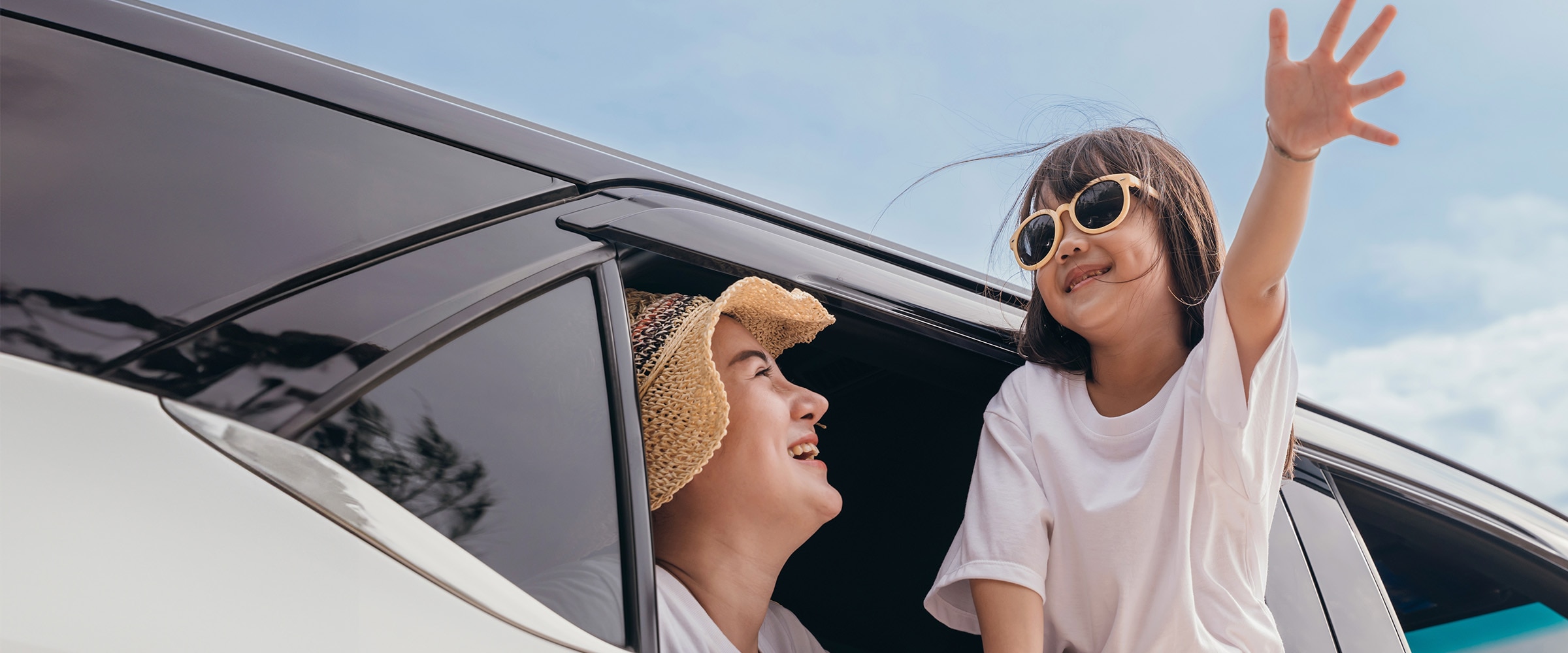 Photo of young girl waving outside a car window.