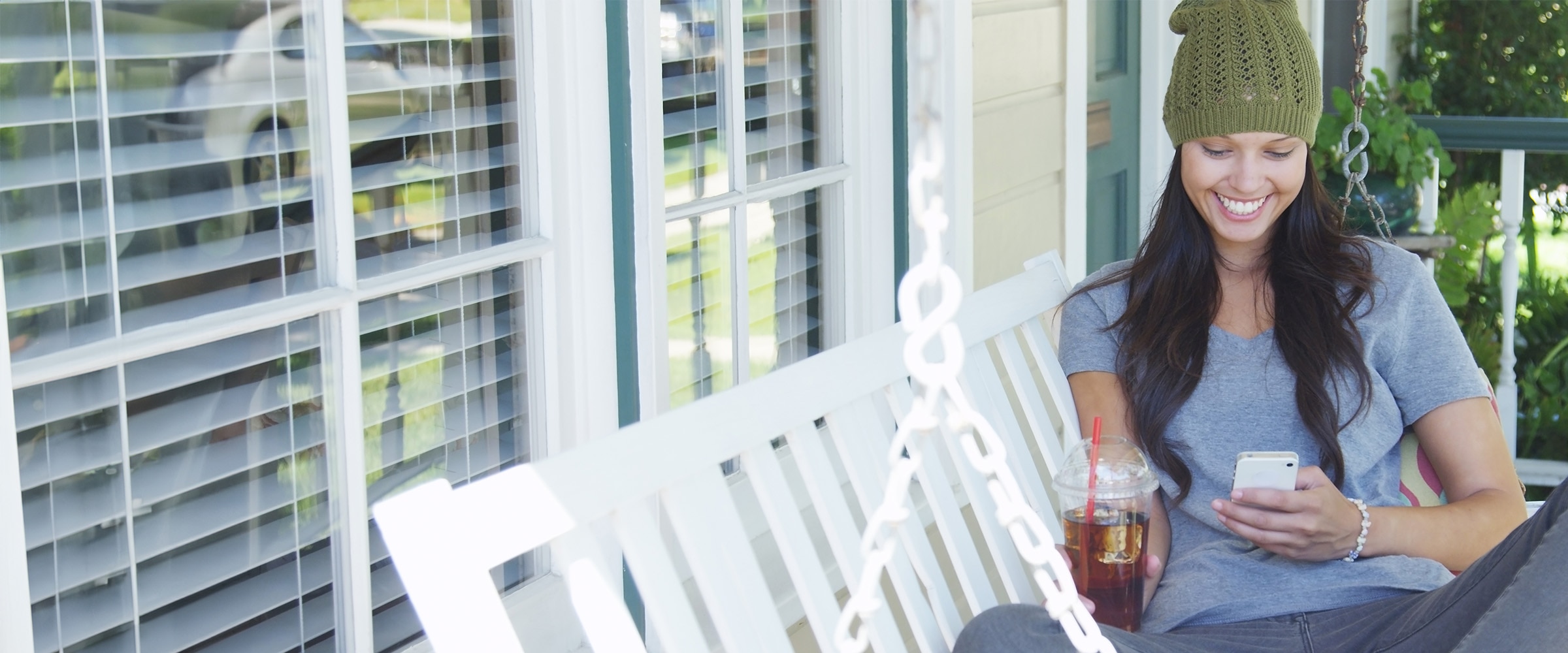 Photo of a woman on a porch looking at her smartphone.