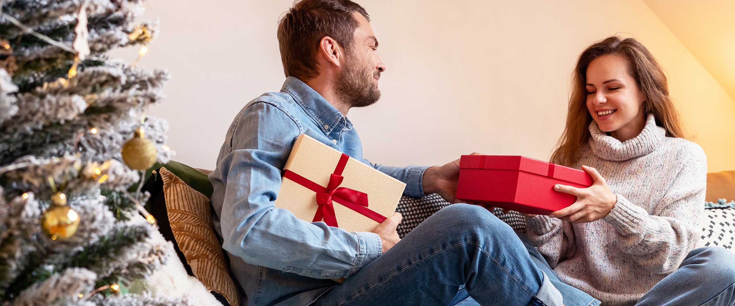 Photo of couple on the couch sharing holiday gifts.