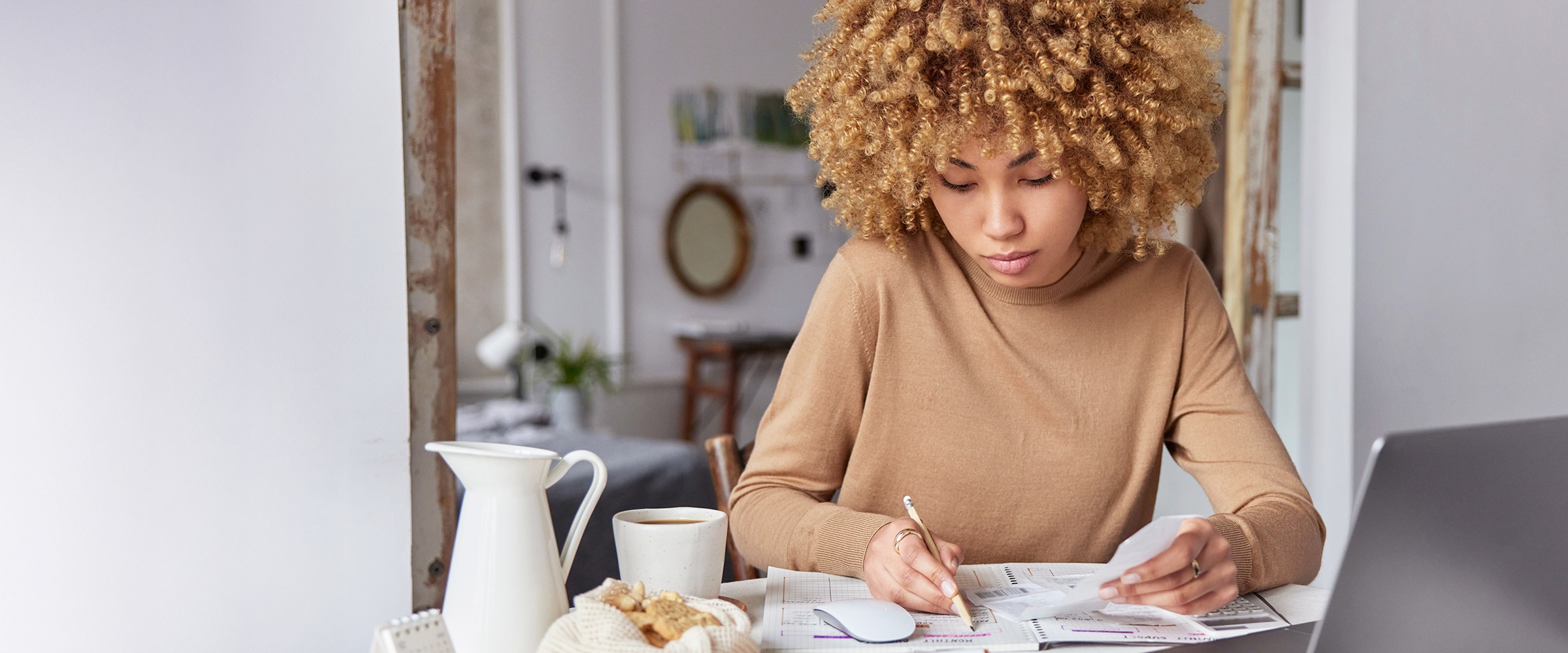 Photo of African-American woman sitting at a table planning her budget.