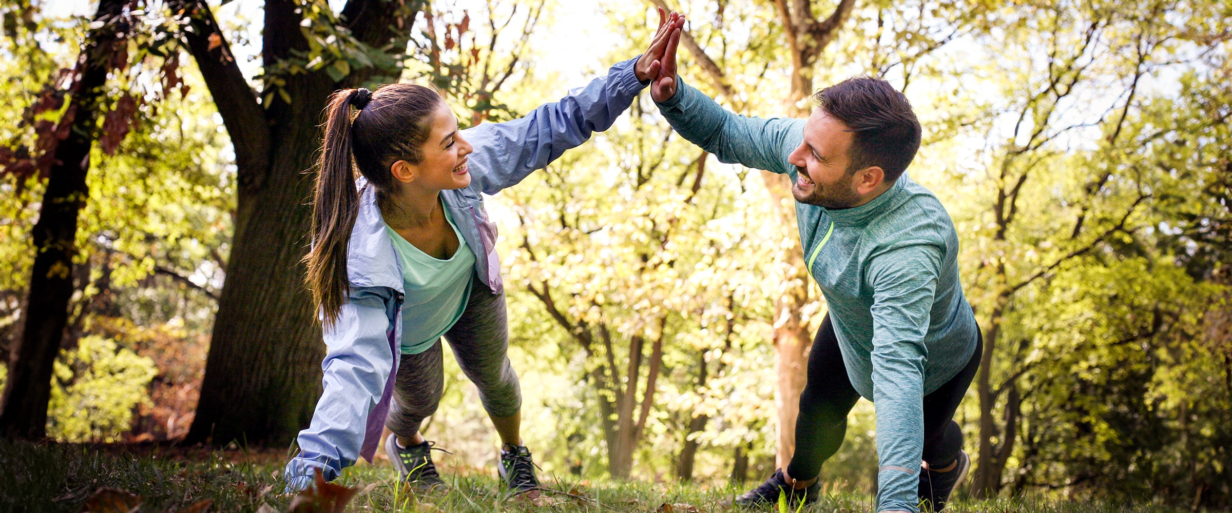 Photo of a young couple enjoying a workout together. They high five each other.