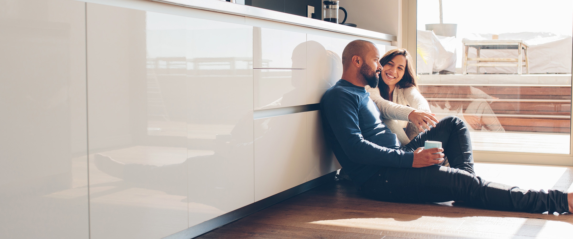 Photo of couple in kitchen on floor leaning up against the dishwasher.