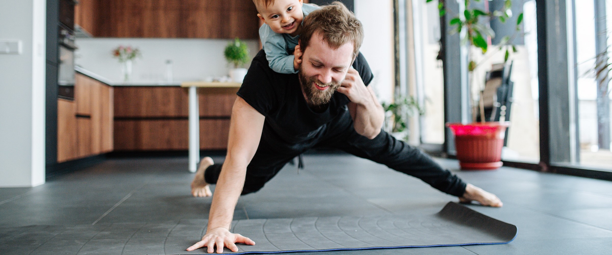 Photo of man doing one-handed push up with small son on his back.