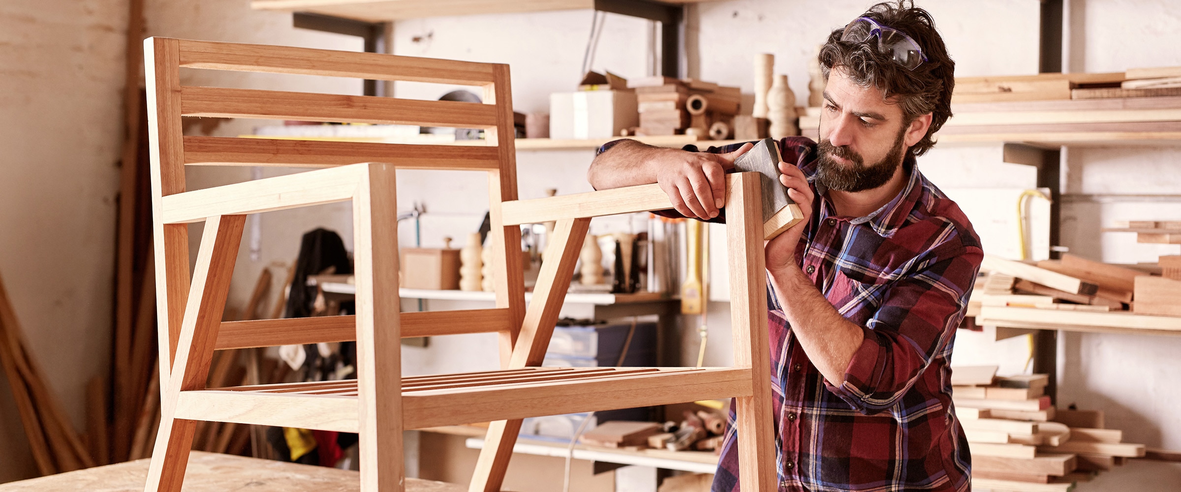 Photo of a male small business craftsperson building a wooden chair.