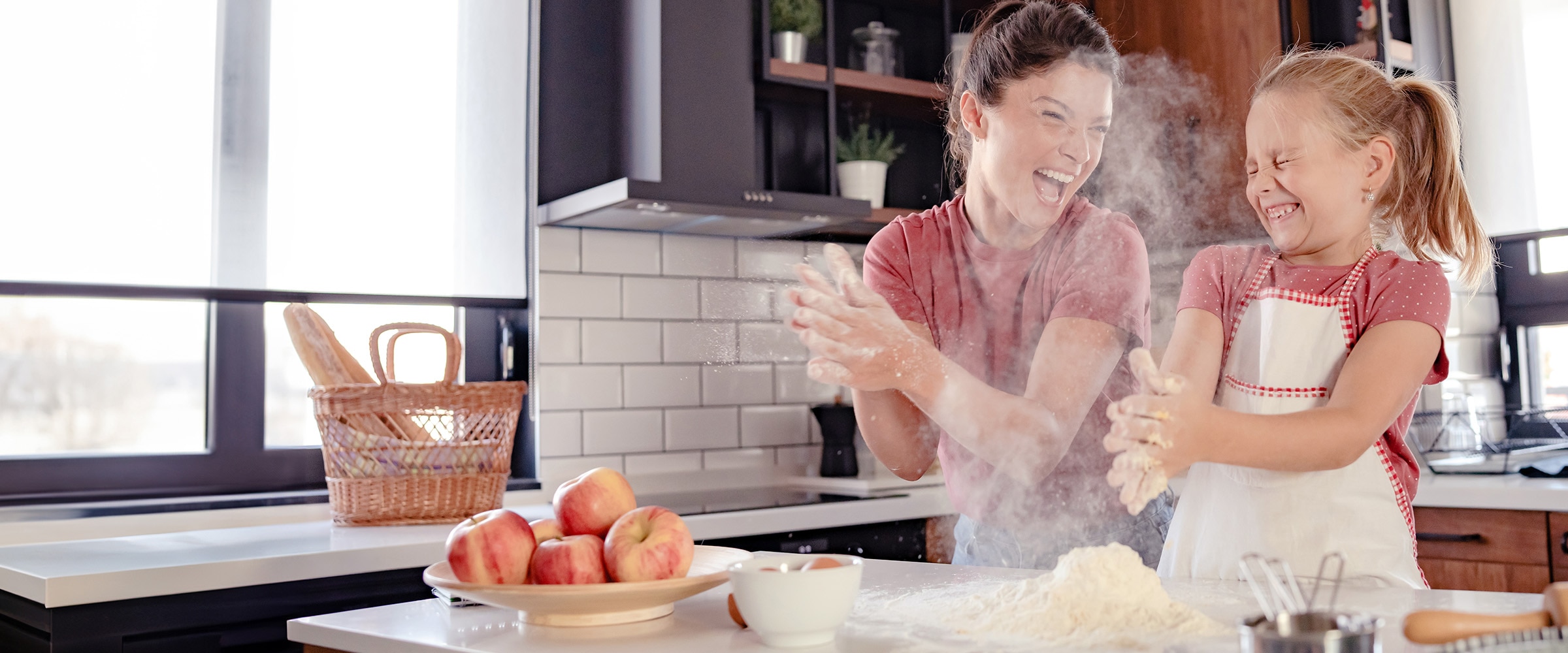 Photo of mom and daughter in kitchen with flour in their hands.