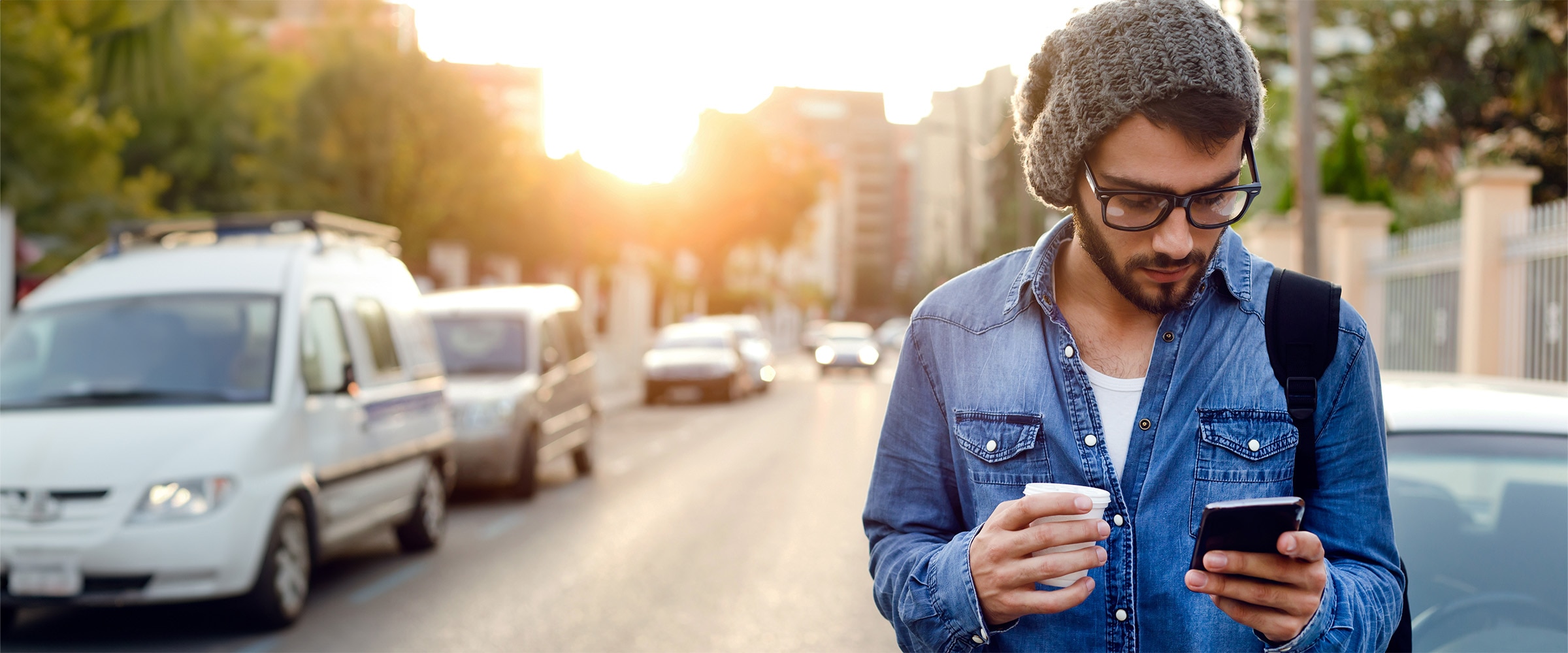 Photo of man walking on the street looking at his phone.