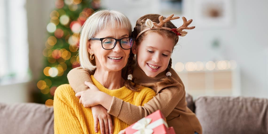 Photo of woman opening gift and being hugged by a child.