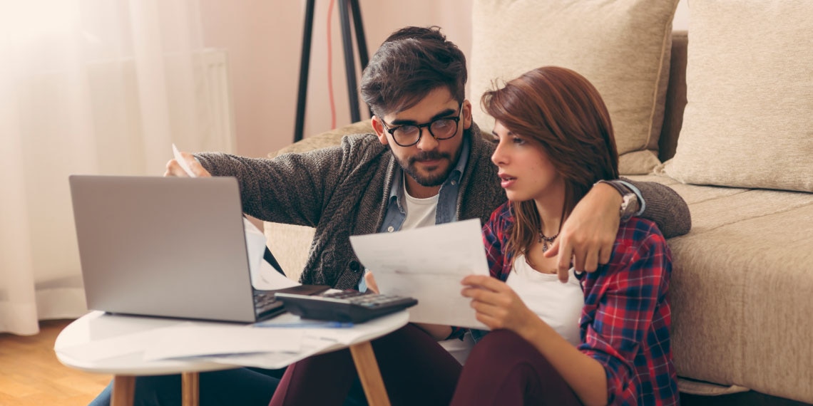 Photo of couple in front of couch looking at computer.