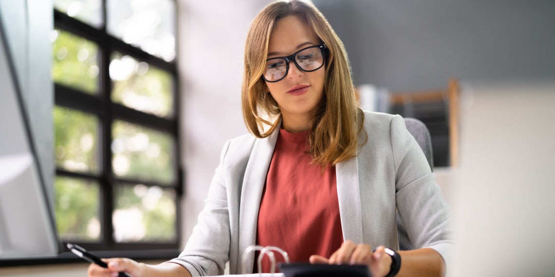 Photo of woman at desk figuring out her saving plan.