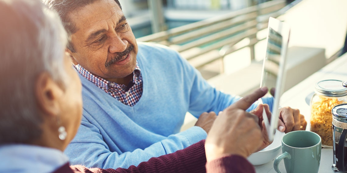 Photo of older couple looking at content on a digital tablet.