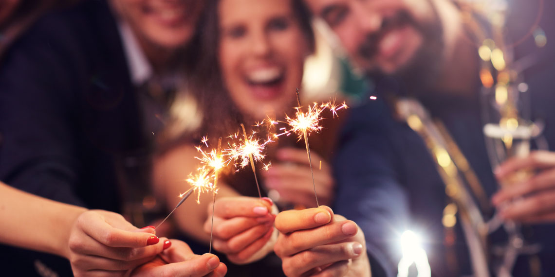 Photo of hands holding up live sparklers to celebrate the new year.