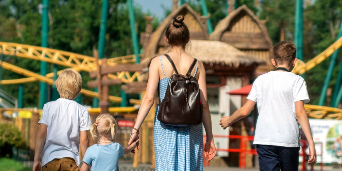 Photo of mother and three kids walking into an amusement park.