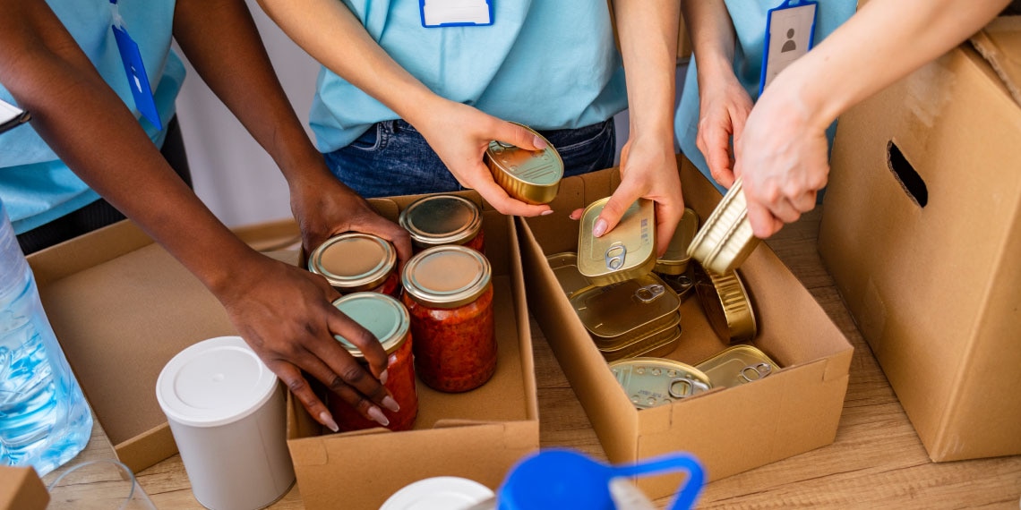 Photo of hands placing donated goods in boxes.