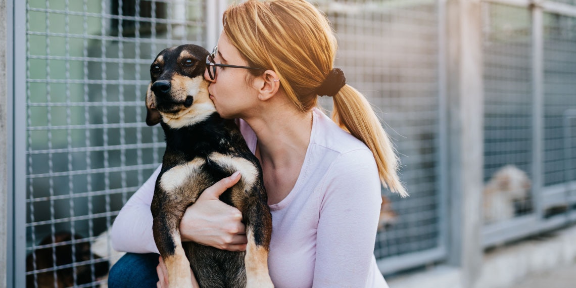 Photo of woman holding and kissing her dog.