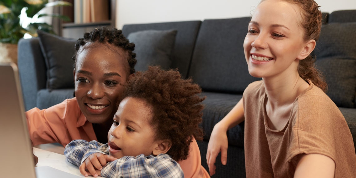 Female couple looking at computer with their child.