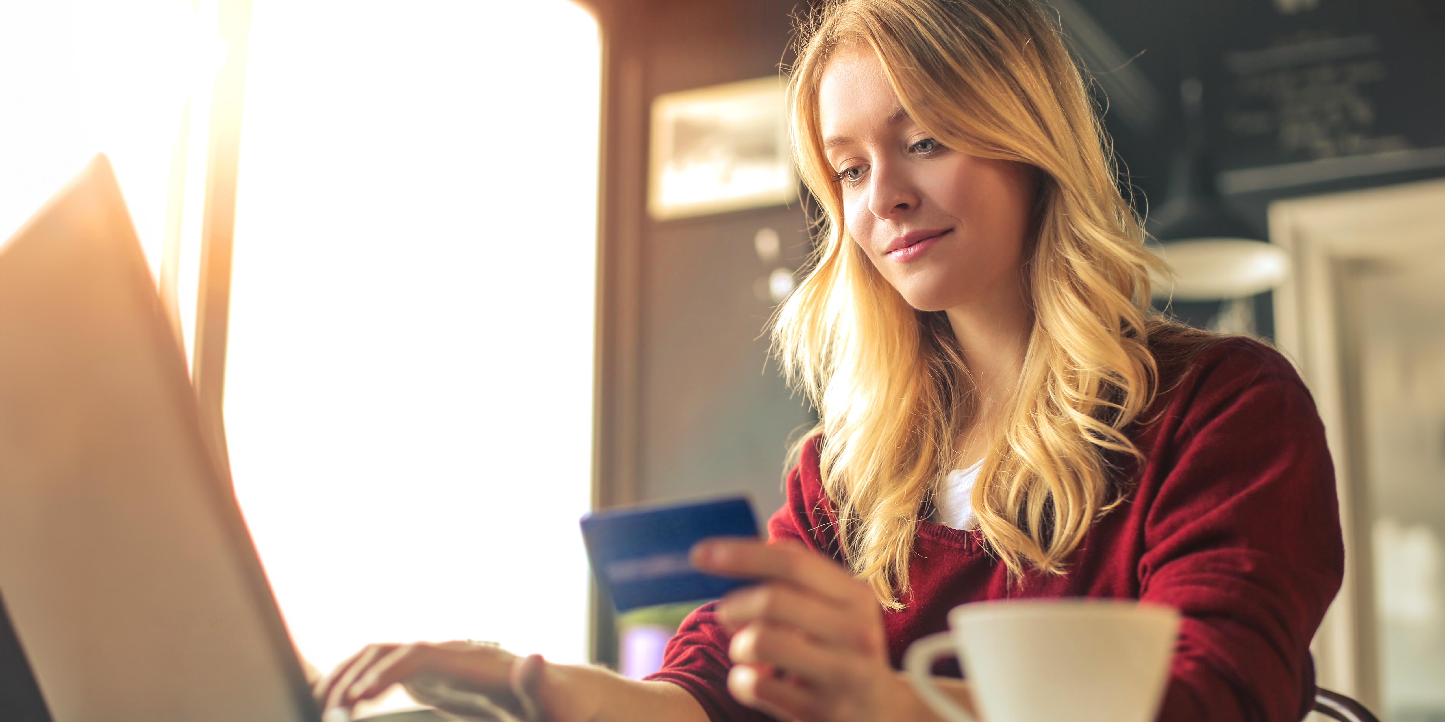 Photo of woman at computer looking at her laptop and holding a credit card.